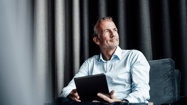 Man sitting in a chair holding a tablet.