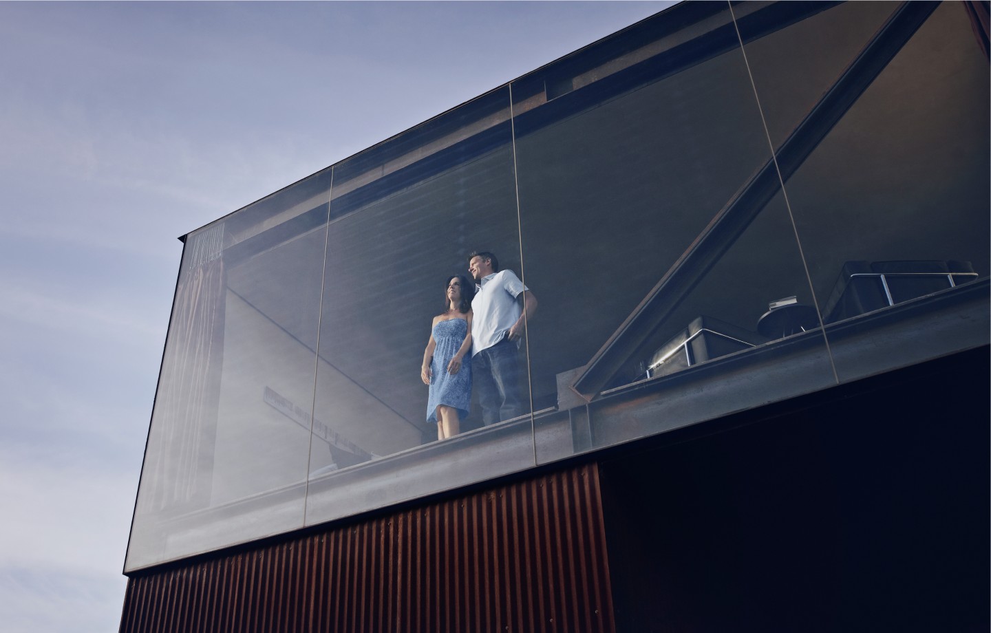 Man and woman looking at the glass window from inside a building
