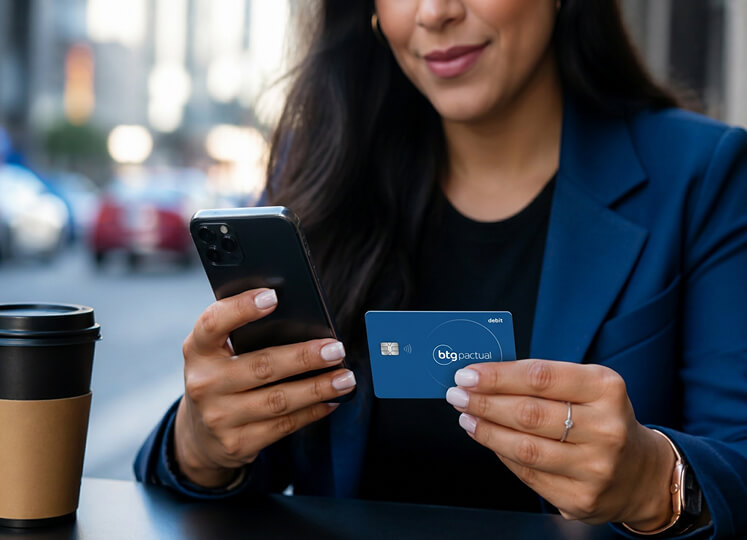 Persona sosteniendo un teléfono móvil y una tarjeta BTG