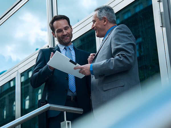 Two men talking while looking at a sheet of paper.