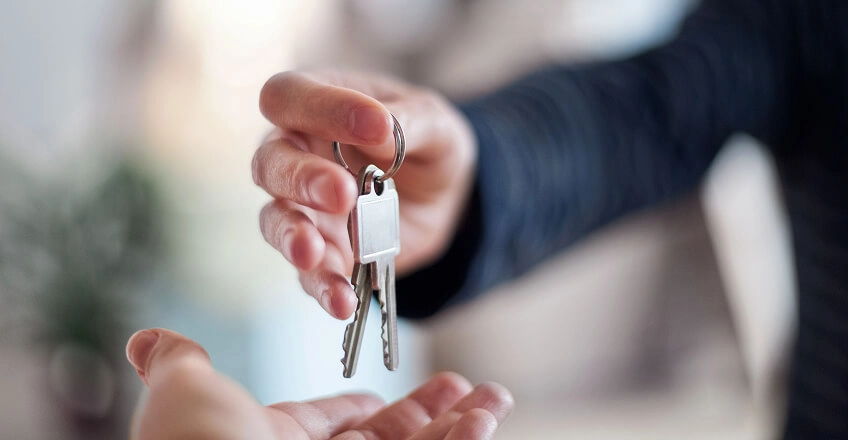 One person handing keys to another.