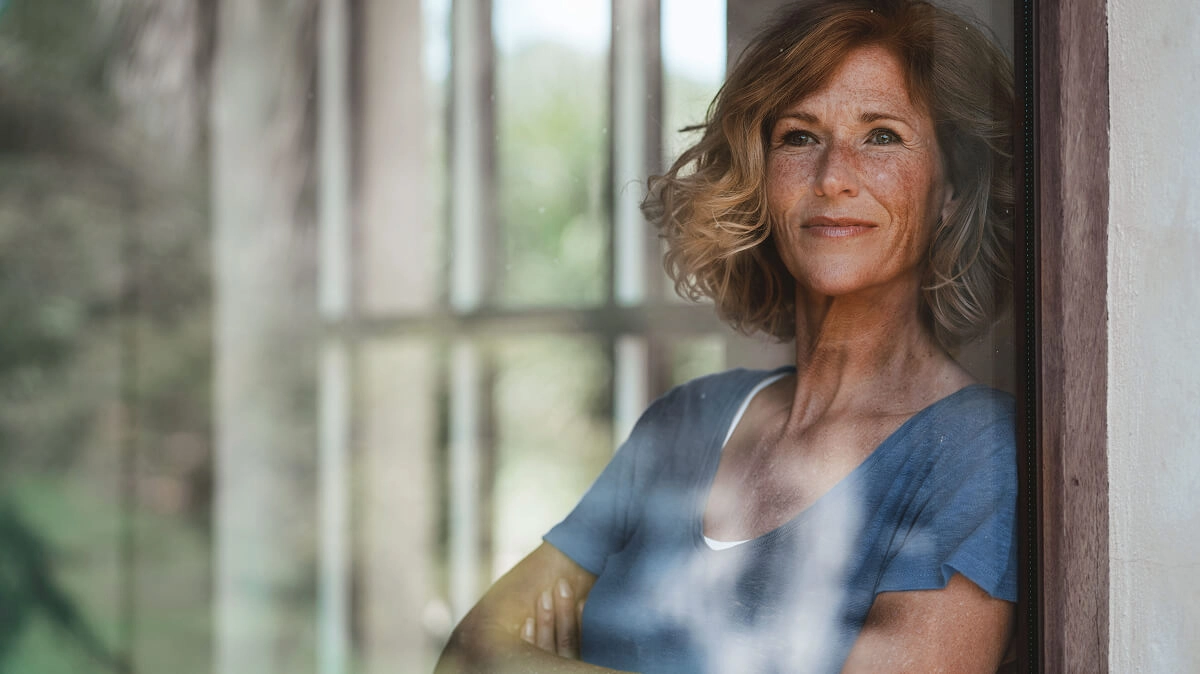 Woman smiling, looking out the window.