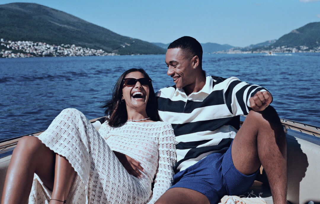 Smiling couple relaxing on a boat on a lake.
