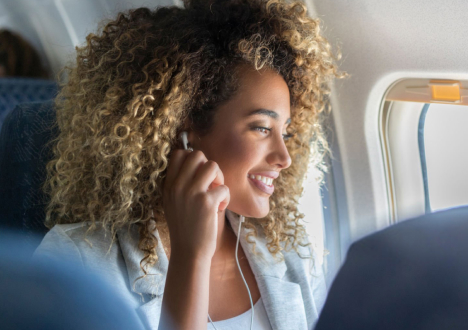 Woman on a plane wearing headphones and smiling